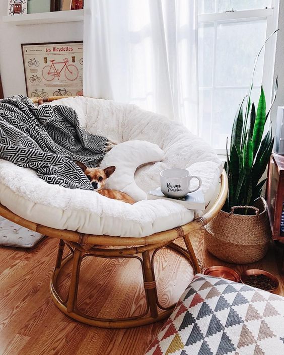 a round rattan chair with cushions and pillows plus a fur throw is extremely cozy to enjoy reading by the window