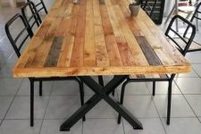 22 a stylish dining table with criss-cross metal legs and a pallet wood tabletop and black metal chairs