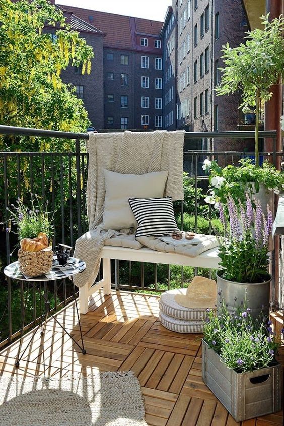 potted greenery and blooms, a rug and pillows and baskets make this balcony welcoming