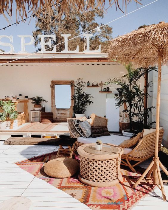 một hiên nhiệt đới với đồ nội thất mây, lòng bàn tay trong chậu, gối, thảm boho và một chiếc ô trên giường một hiên nhiệt đới với đồ nội thất mây, lòng bàn tay trong chậu, gối, thảm boho và một chiếc ô trên giường