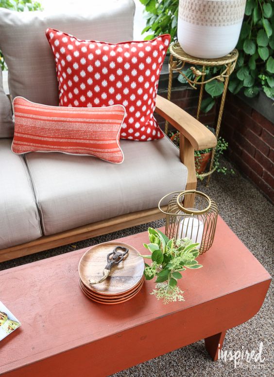colorful pillows, a candle lantern and potted greenery make up the whole space sprucing it up