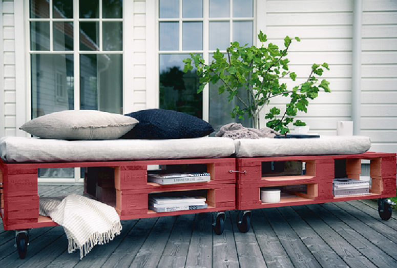 a bright red pallet daybed with cutout storage spaces, casters and comfy cushions
