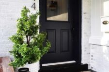 25 a white planter with a mini tree and black candle lanterns plus a black door for a stylish modern look