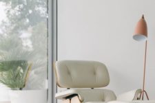 26 Eames lounge chair of plywood and white leather and a matching footrest by the window