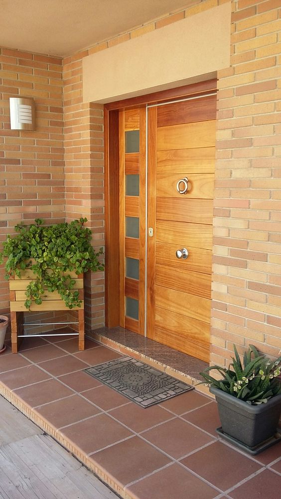 a wooden planter on tall legs and a small grey planter with different types of greenery to frame the door