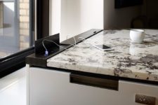 26 oxidized metal enclosure provides the charging ports in this uber-contemporary kitchen without compromising on design