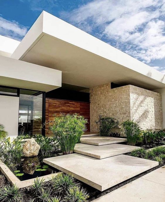 a beautiful modern front yard with a stone ladder, a small pond with greenery and a large rock and some water plants, too