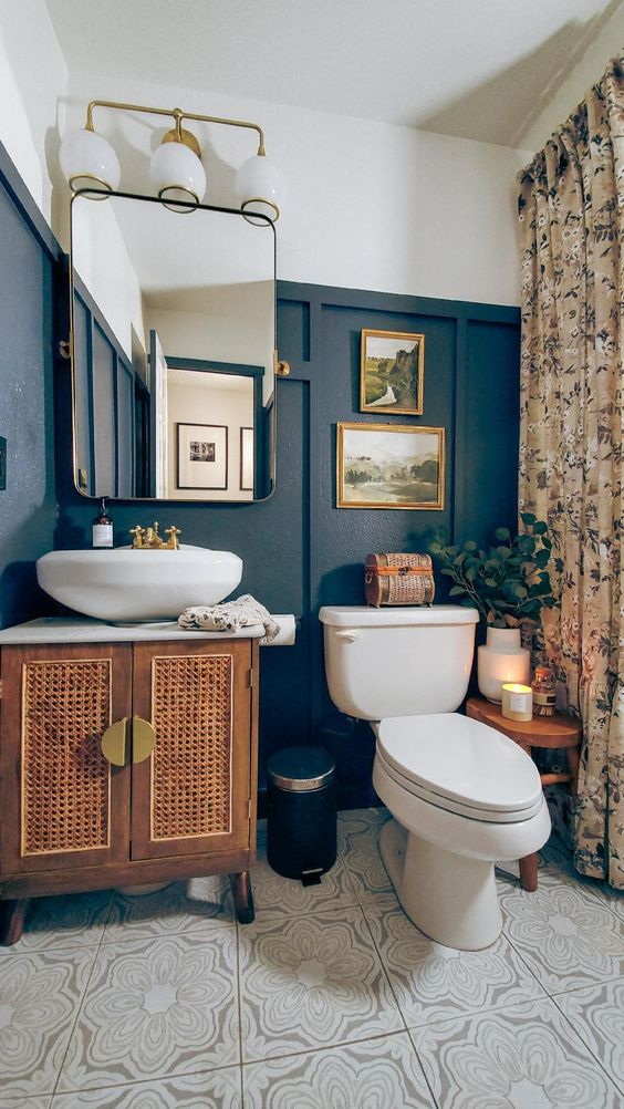 a catchy eclectic bathroom with black paneling, a cane vanity, a sink, a mirror wth lights and a floral print curtain