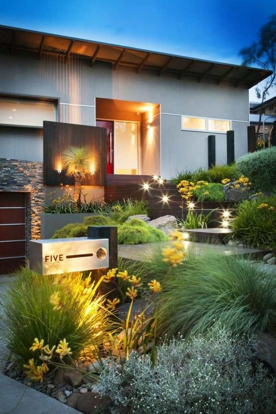 a chic modern front yard with rocks and a wooden deck, various plants with plenty of texture, lights and a cool house number