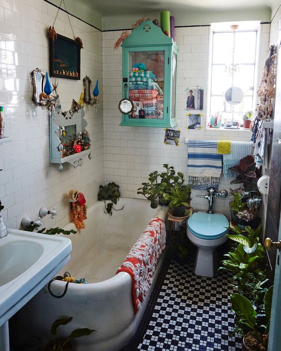 a crazily eclectic bathroom with white and black and white tiles, a tub, a sink, a toilet, some bold textiles, plants and decor