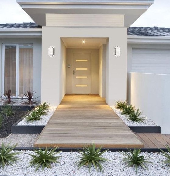 a delicate front yard with white pebbles, succulents and dark succulents, with a deck that leads to the entrance is a very chic and laconic space