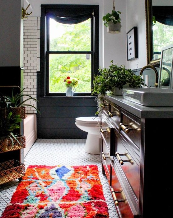 a lovely eclectic bathroom with subway and fishscale tiles, a bold rug, potted plants and touches of black and green