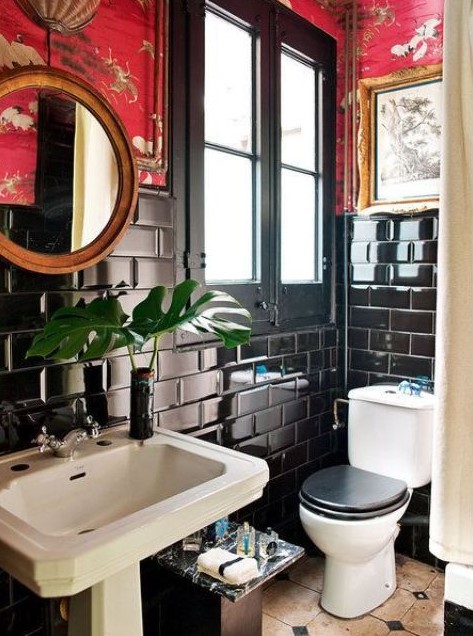 a maximalist bathroom with black subway tiles, red printed wallpaper, a round mirror, artworks and white appliances