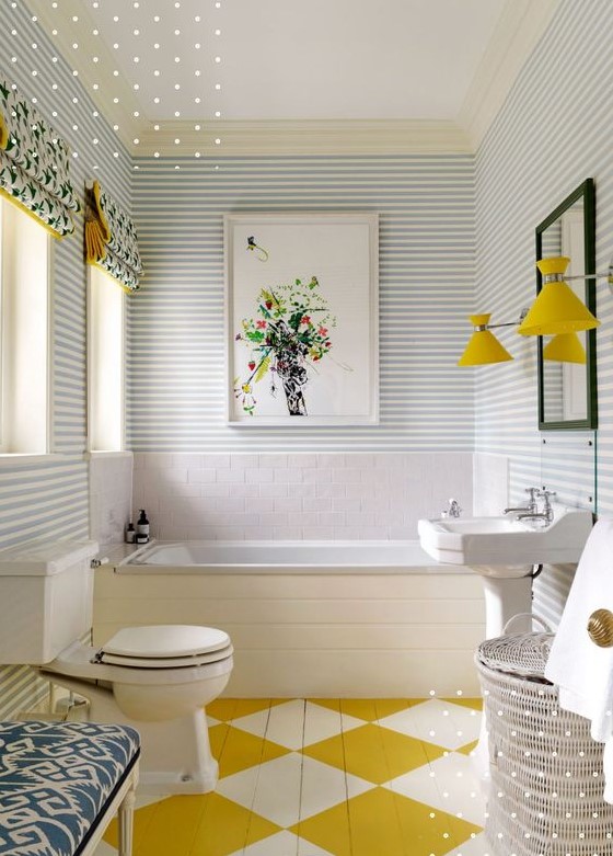 a maximalist bathroom with striped walls, a geo painted floor, an upholstered bench, some baskets, yellow lamps and printed curtains