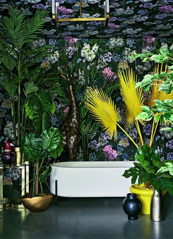 a maximalist space with dark floral wallpaper, bold statement plants in green and yellow, brass touches and vases