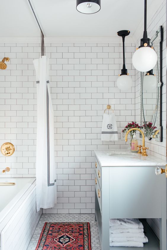 a mid-century meets boho bathroom with a colorful boho rug, gilded touches and pendant lamps and a curtain