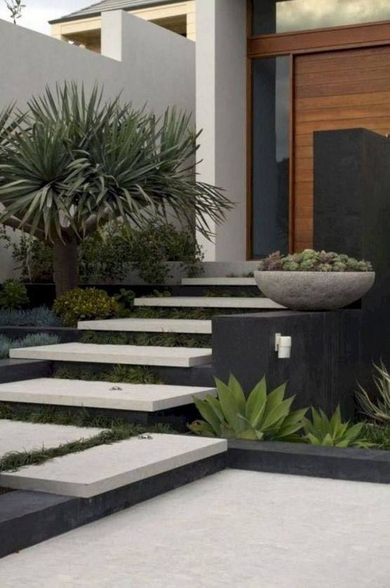 a modern front yard with neutral steps and greenery in between the steps, with trees and succulents around is a chc and bold space