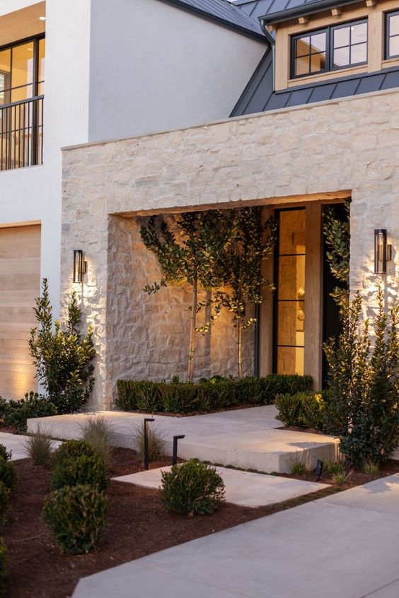 a stylish modern front yard with some greenery that is perfectly cut, with lights and bushes is a lovely space