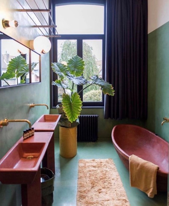 a vibrant bathroom done with aqua-colored walls and a floor, pink sinks and a bathtub, gold fixtures and a black curtain