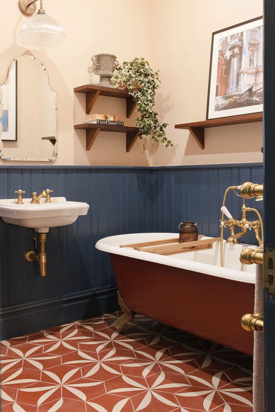 a boho bathroom with white walls and navy paneling, a rust-colored bathtub, a wall-mounted sink and some open shelves