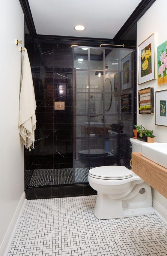 an eclectic bathroom done with black and white tiles, a floating vanity, white appliances and a colorful gallery wall