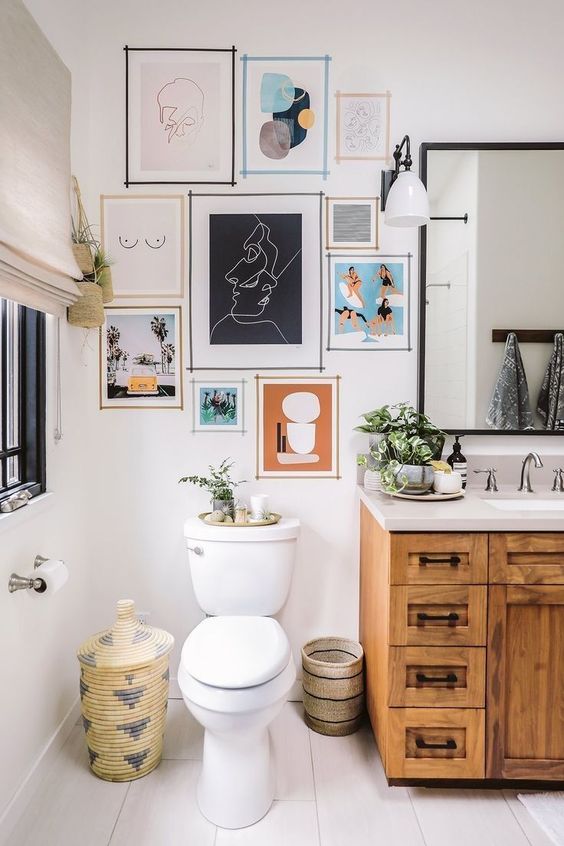 an eclectic bathroom with a stained vanity, a bright gallery wall, a basket with a neutral curtain on the wall