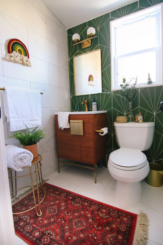 an eclectic bathroom with a white tile and green tile wall, a stained vanity, white appliances, brass lamps and potted greenery