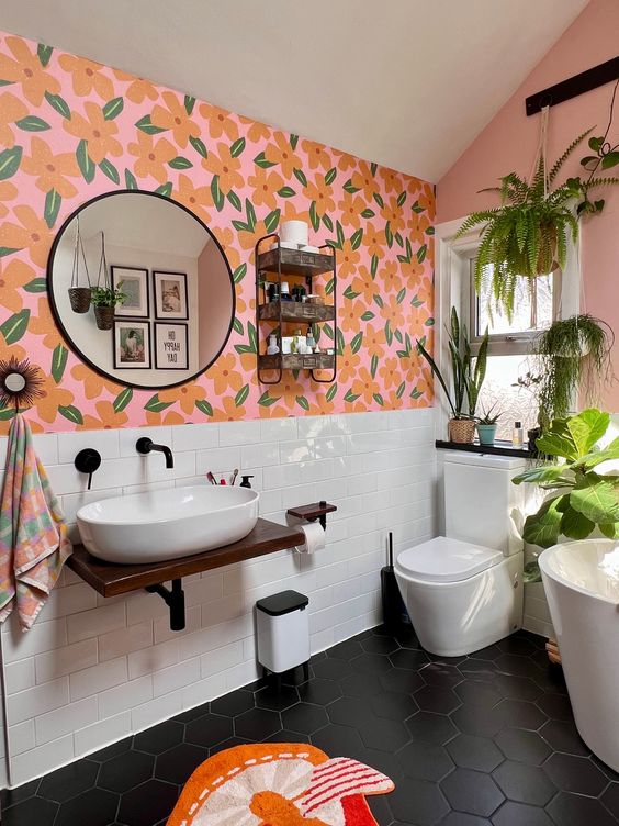 an eclectic bathroom with bold floral wallpaper, white subway tiles, white appliances, potted greenery and a shelf on the wall