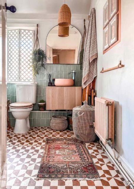 an eclectic bathroom with green and rust and white tile, white appliances, a stained vanity, a mirror, a woven pendant lamp and a gallery wall