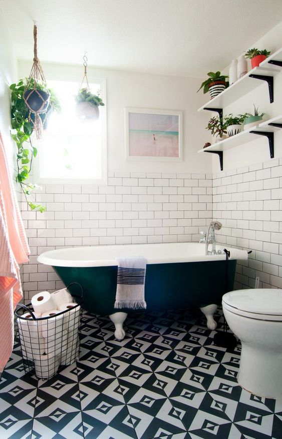 an eclectic bathroom with potted greenery, black and white tiles on the floor and touches of blush