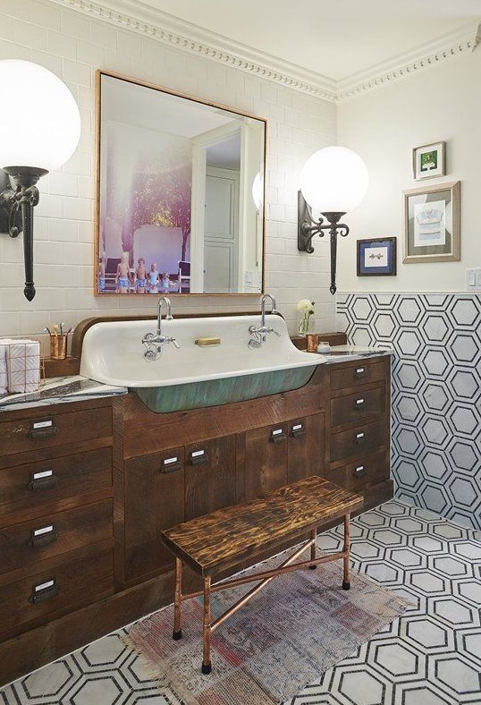 an eclectic bathroom with subway and hexagon tiles, a dark-stained vanity, a stool, a gallery wall and large sconces