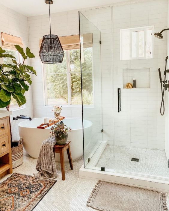 an eclectic bathroom with white tile, a stained vanity, a soak tub, a shower space, a pendant lamp and some greenery