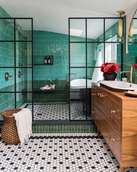 an eye-catchy bathroom with green skinny tiles, black and white hex ones, a stained vanity, a sink and a bathtub is amazing