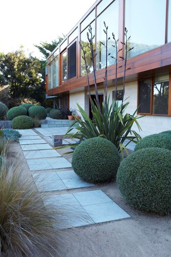 stone tiles, green balls, grasses, tall plants make up a very stylish and chic space in elegant modern style