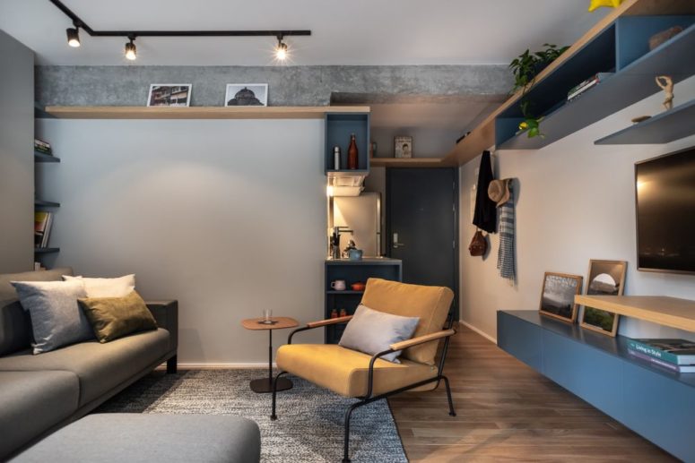 The living room is done in blue and greys, with upholstered and leather furniture, with lights and a home office space The living room is done in blue and greys, with upholstered and leather furniture, with lights and a home office space