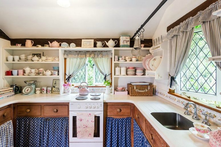 The kitchen is done with lots of built-in shelves, rich-stained cabinets with polka dot fabric covers and small windows