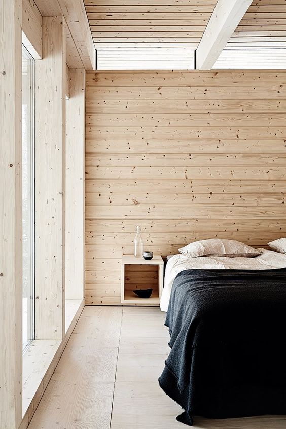 a minimal Scandinavian bedroom with wooden walls, a floor and ceiling that make the space welcoming