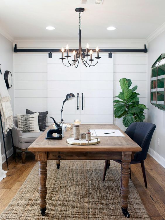 a farmhouse home office with white shiplap on the accent wall and vintage furniture, a vintage chandelier and potted greenery