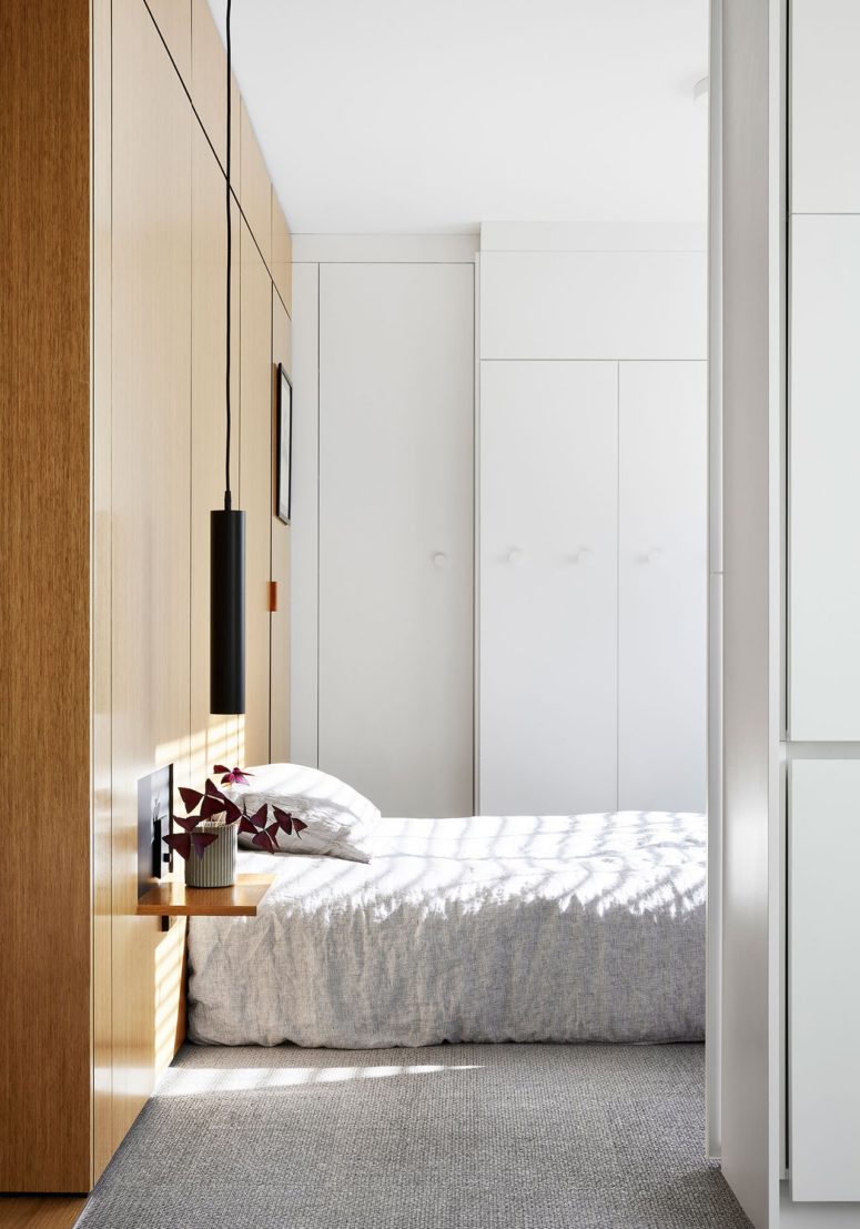 The bedroom is small and laconic, it features a woodne headboard that acts as storage, floating nightstandns and pendant lamps The bedroom is small and laconic, it features a woodne headboard that acts as storage, floating nightstandns and pendant lamps