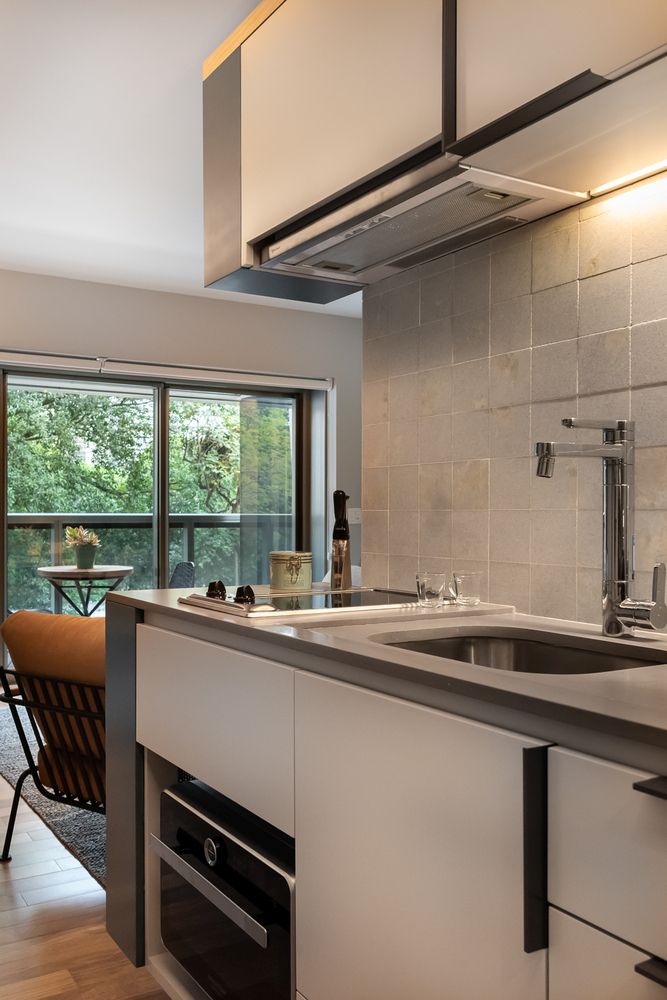 The kitchen is pretty small, there are white sleek cabinets, a neutral tile backsplash and additional lights The kitchen is pretty small, there are white sleek cabinets, a neutral tile backsplash and additional lights