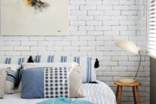 06 a beach-inspired bedroom with a statement white brick wall that highlights the artwork and contrasts the colorful bedding