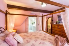 07 One bedroom is done in pink with a large canopy bed and a large wooden dresser