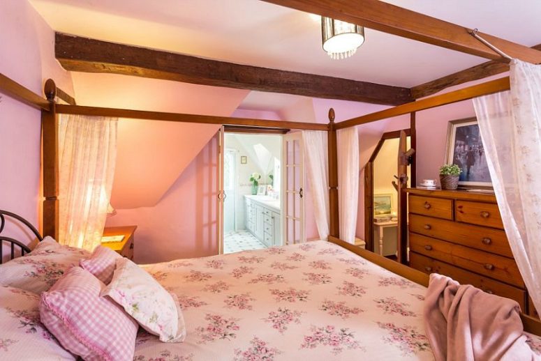 One bedroom is done in pink with a large canopy bed and a large wooden dresser