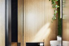 07 The bathroom features a shower and much light-colored wood and black surfaces to continue the color scheme of the apartment