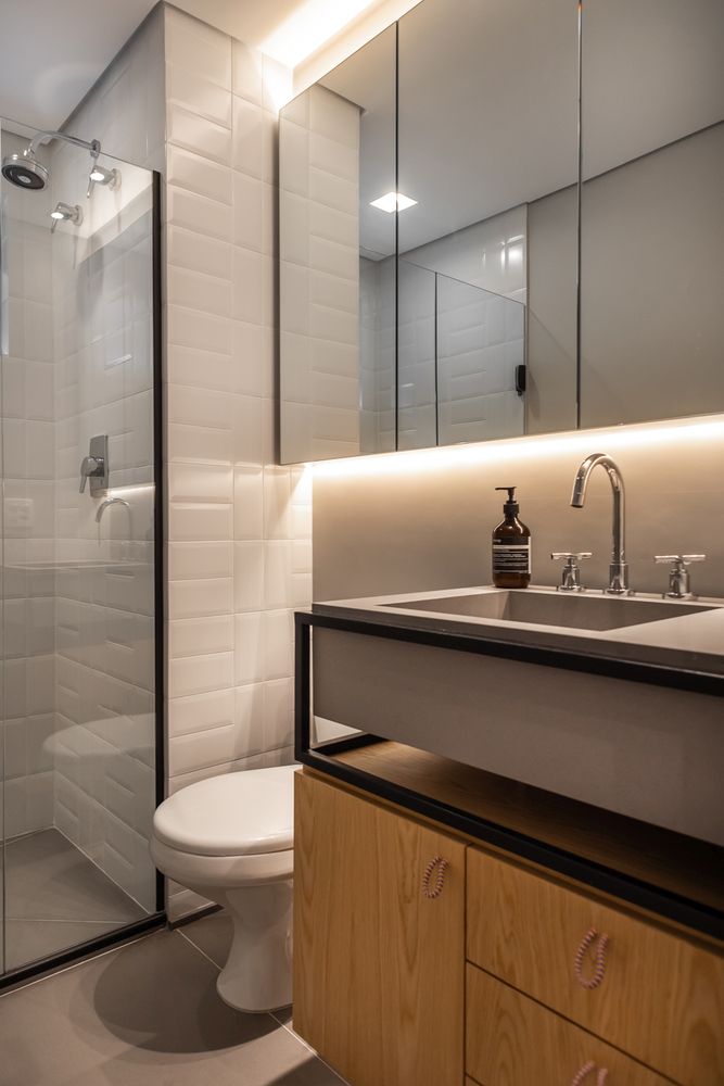 The bathroom is done with white with black touches for drama, a wooden vanity, a concrete sink and a large mirrored cabinet The bathroom is done with white with black touches for drama, a wooden vanity, a concrete sink and a large mirrored cabinet