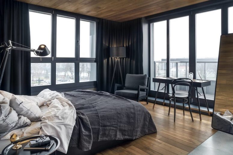 The master bedroom is paired with a sleek desk by the wiindow, there are dark textiles and much natural light The master bedroom is paired with a sleek desk by the wiindow, there are dark textiles and much natural light