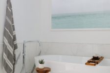 08 a fresh and airy bathroom done in white and creamy shades, with light greys and an aqua artwork showing the sea