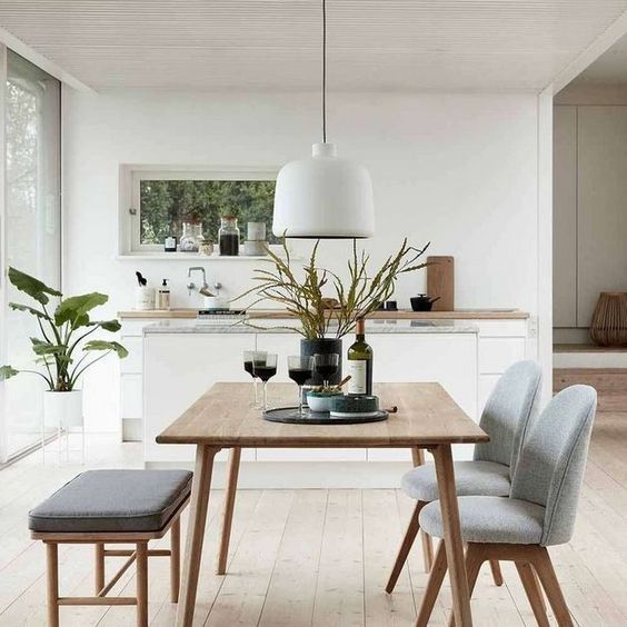 a contemporary wooden dining table with grey upholstered chairs and a seating with darker upholstery for a fresh look