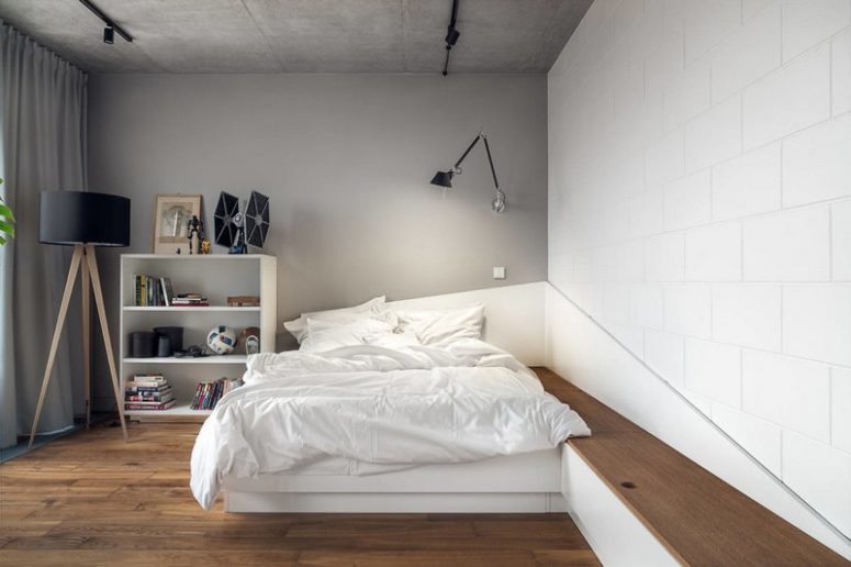The second bedroom features a unique platform bed, a storage unit, some lamps and concrete