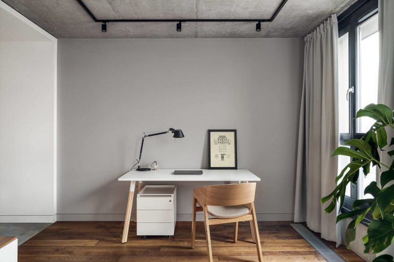 There's also a home office space by the window, with a sleek white desk and a chair